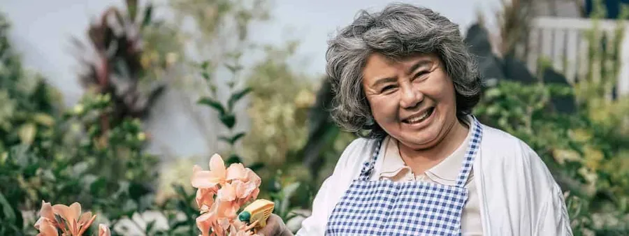 Senior woman gathering flowers in garden